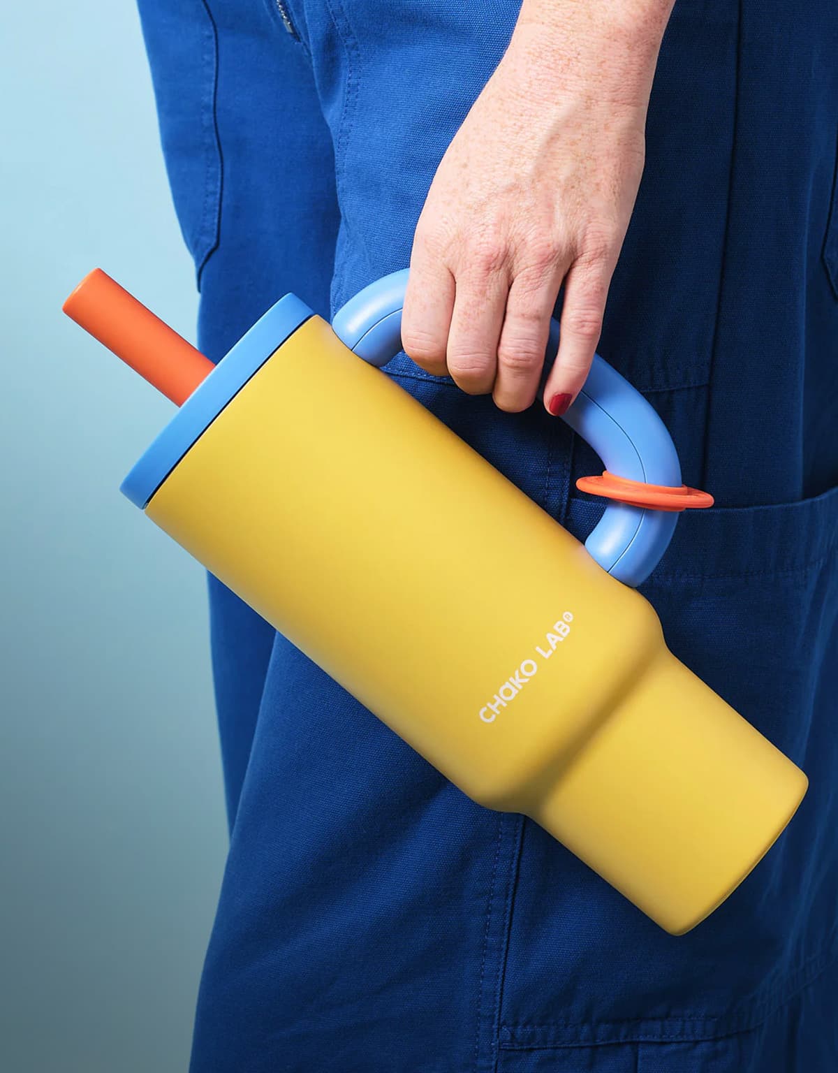 Hand holding a yellow Chako Lab tumbler by its handle
